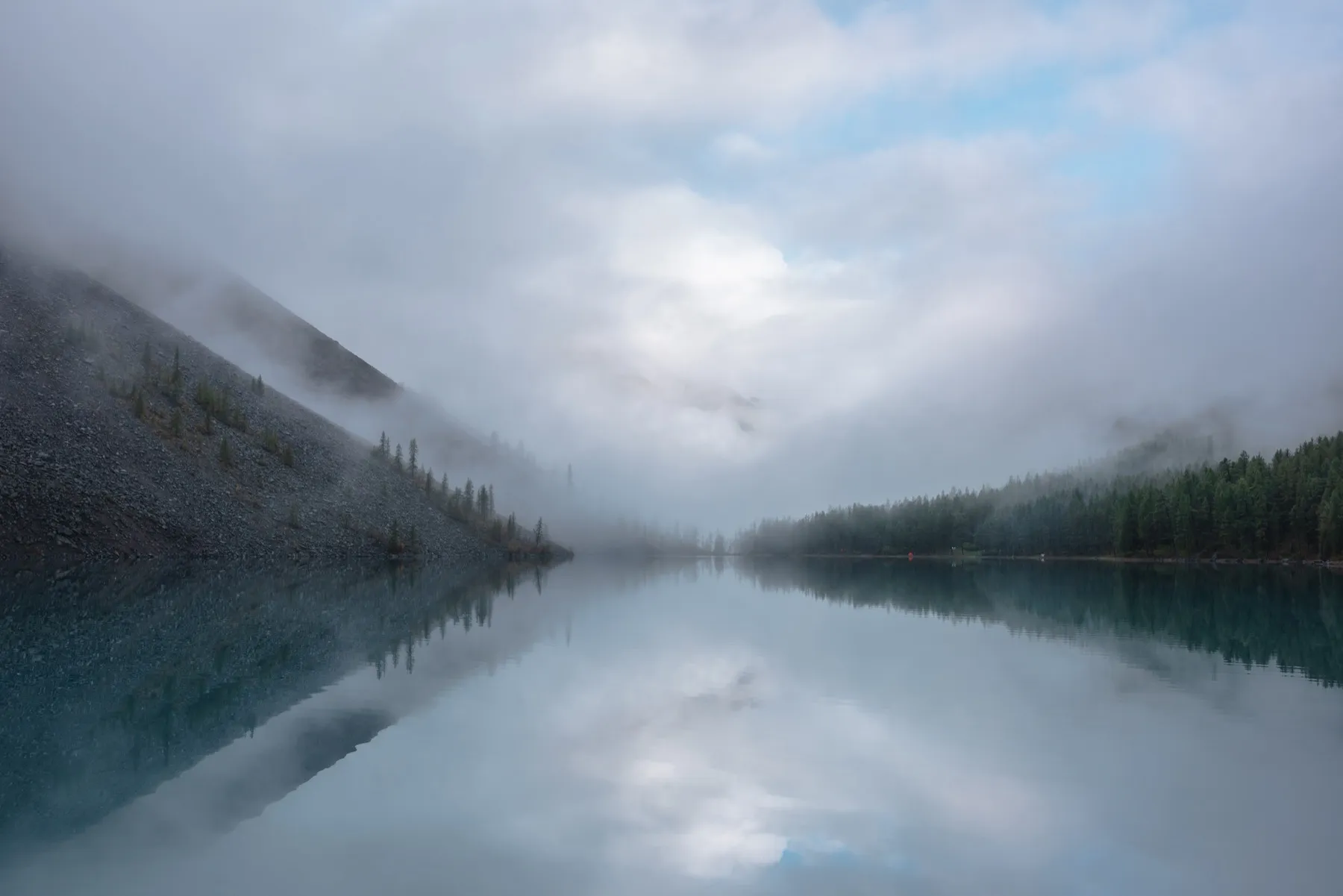 Lac glaciaire suisse au petit matin, brume sur les sapins, lumière froide.